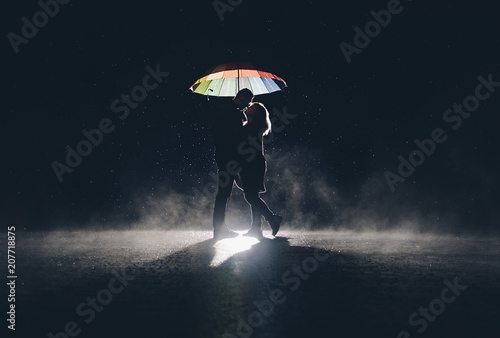 lovers under at colorful umbrella in the rain at night. photo