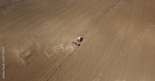 aerial view of harvest field with agricultural machinery carrying out work in the field