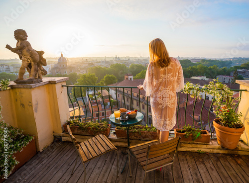 Photography Woman standing on balcony and overlooking city in early morning