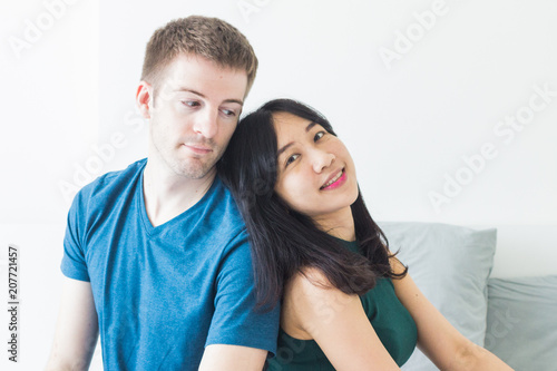 Couple with good communication skills.  White background laying on bed and happy. © Travis