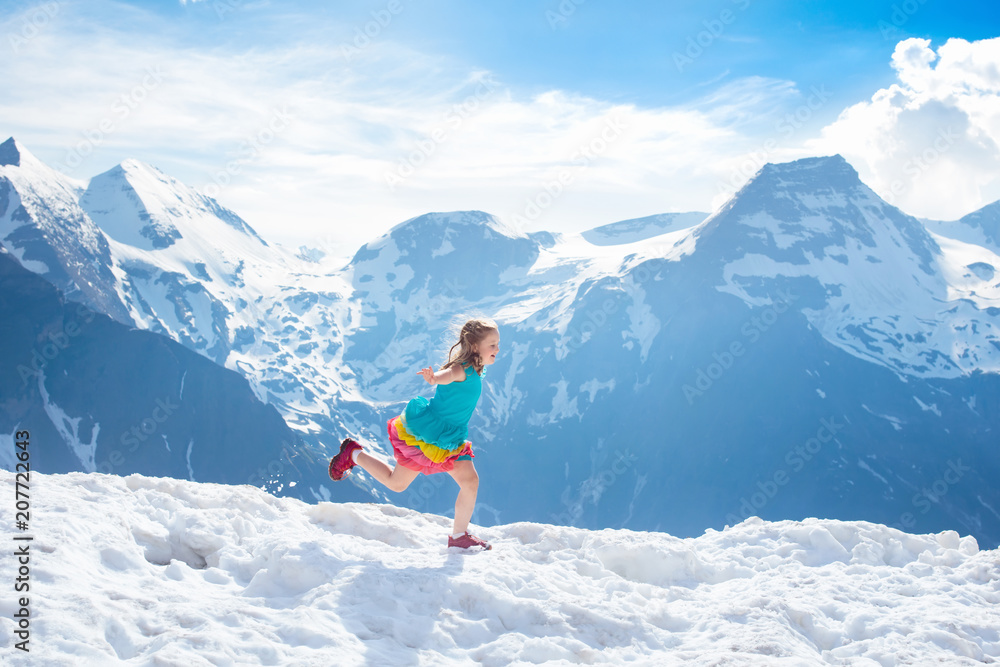 Child hiking in mountains. Kids in snow in spring.