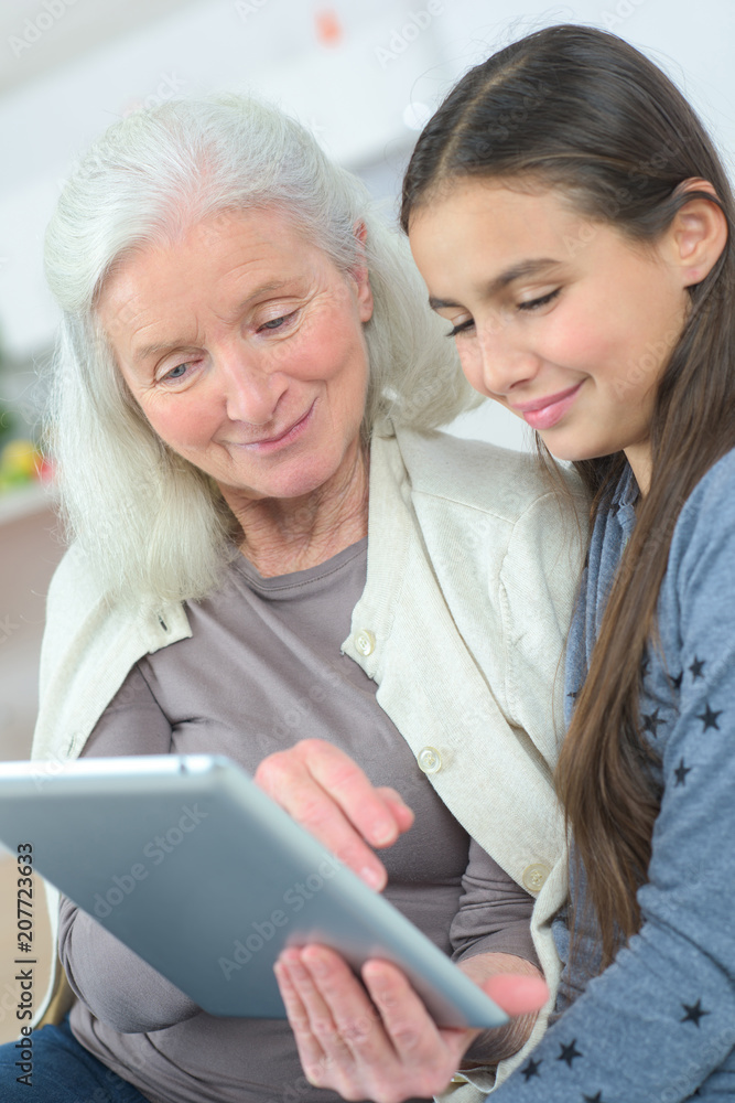 grandmother with grand daughter watching something on a tablet grandmother with grand daughter watching something on a tablet