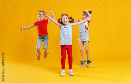 funny children girls jumping on colored yellow background