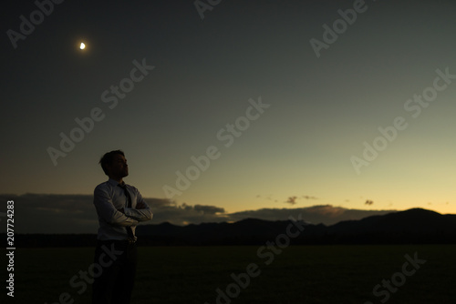 Businessman at sunset standing outdoors with folded arms
