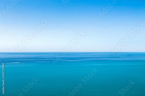 Beautiful blue unearthly seascape with clear sky and unusual stripes on the surface of the water