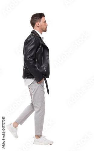 Side view of going handsome man in a leather jacket and trouser