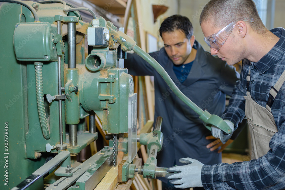 engineer and apprentice using machinery in factory engineer and apprentice using machinery in factory