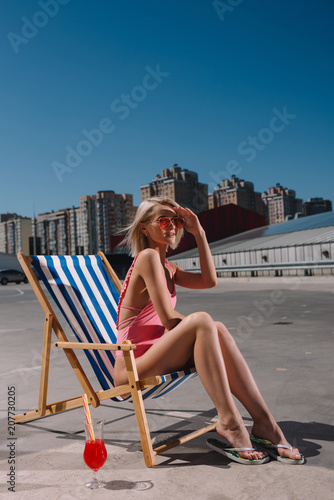 stylish young woman relaxing in sun lounger on parking