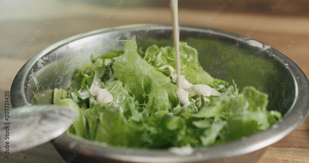 closeup mixing frillis salad leaves with caesar sauce closeup mixing frillis salad leaves with caesar sauce