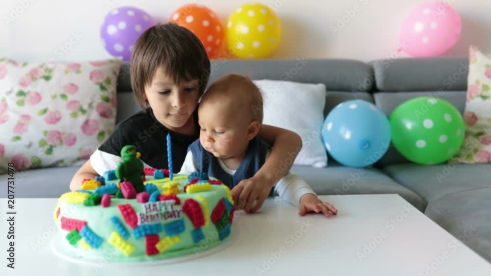 Cute children, boy brothers, celebrating birthday with colorful cake, candles, balloons at home Cute children, boy brothers, celebrating birthday with colorful cake, candles, balloons at home