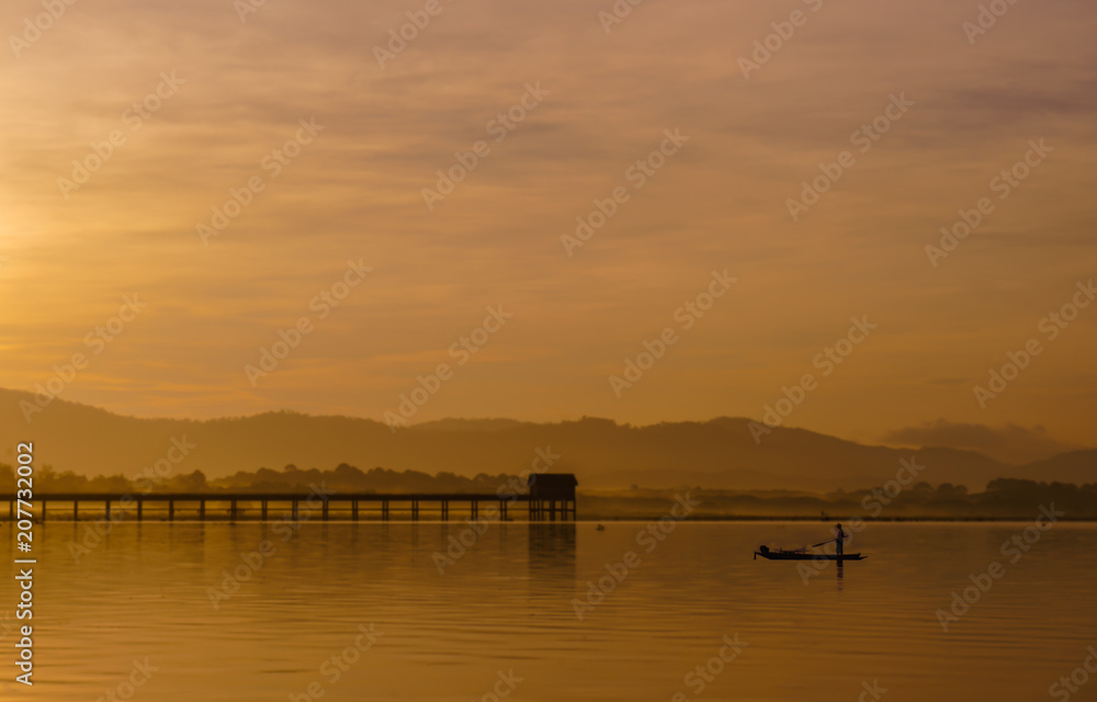 Men are fishing on a boat in a reservoir in the morning.