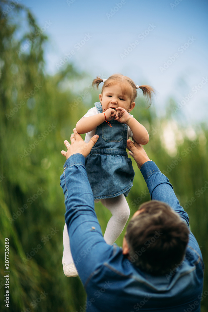 Fototapeta premium Dad and daughter dressed in jeans walking in the pakr and have fun