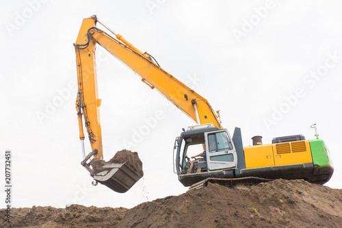 Excavator makes noise barrier with sandy soil