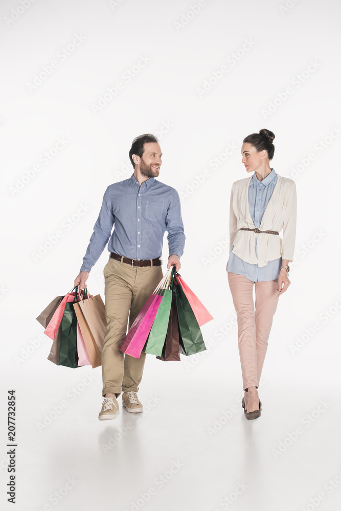woman looking at smiling husband carrying shopping bags isolated on white woman looking at smiling husband carrying shopping bags isolated on white