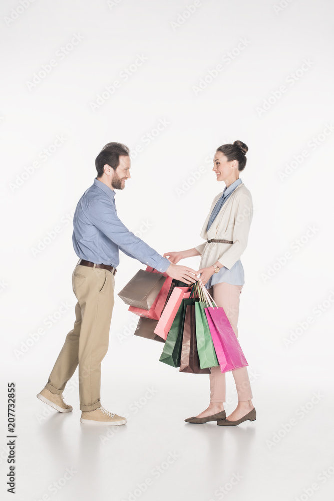 side view of smiling man taking shopping bags from wife isolated on white side view of smiling man taking shopping bags from wife isolated on white