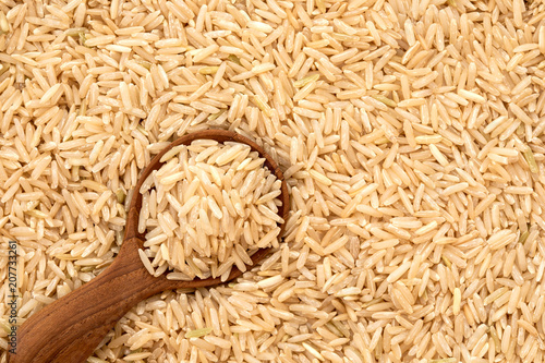 Brown rice in wooden spoon on rice seed background