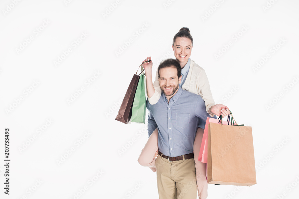 happy woman with shopping bags and husband piggybacking together isolated on white happy woman with shopping bags and husband piggybacking together isolated on white