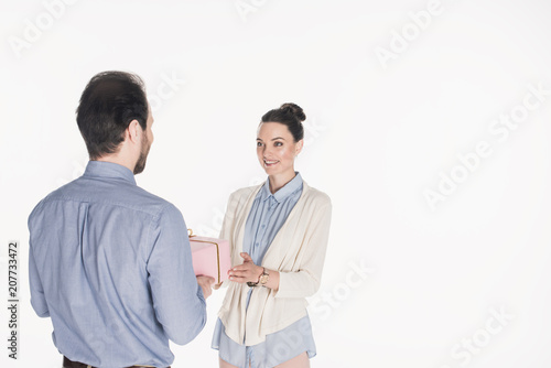 partial view of man presenting wrapped gift to smiling wife isolated on white