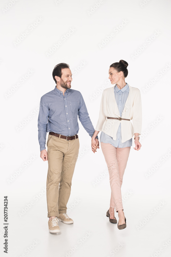 smiling wife and husband holding hands and looking at each other while walking isolated on white smiling wife and husband holding hands and looking at each other while walking isolated on white