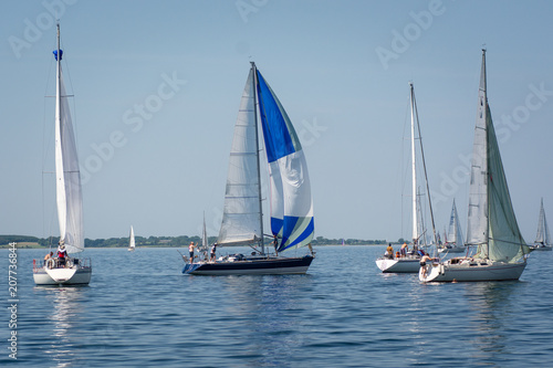 Sailboats stuck on a flat ocean due to no wind. People start to bath instead.