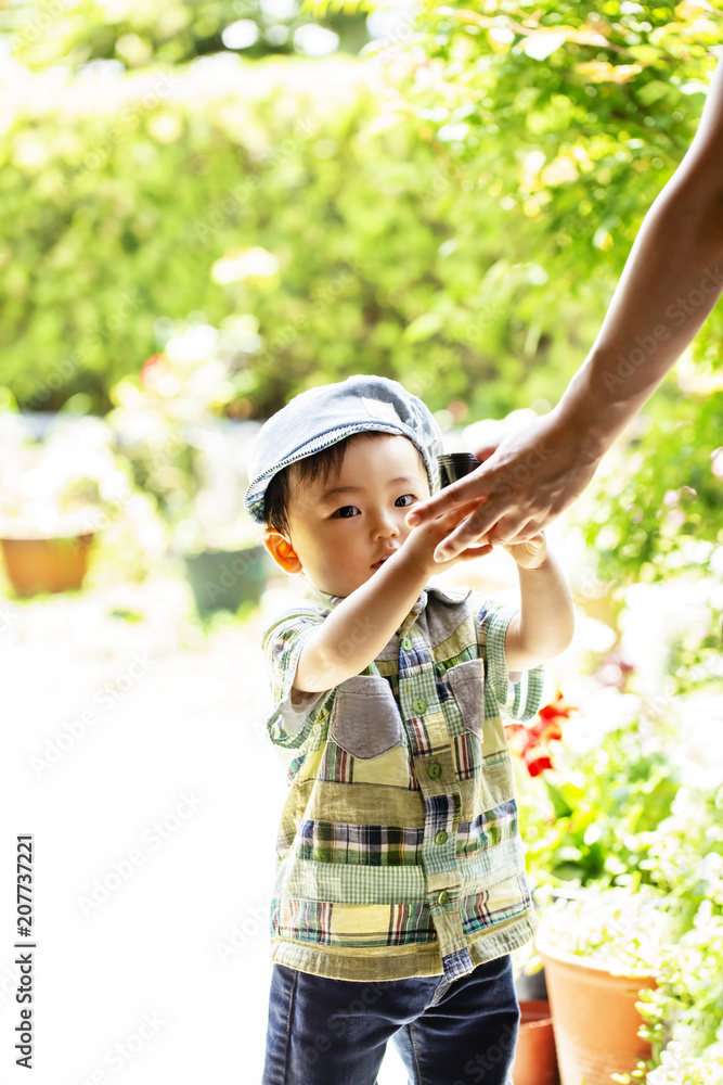 小さな男の子が土の入った黒いポットをお母さんに渡そうと歩いている 小さな男の子が土の入った黒いポットをお母さんに渡そうと歩いている