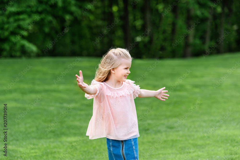 cute happy little child with open arms looking away in park cute happy little child with open arms looking away in park