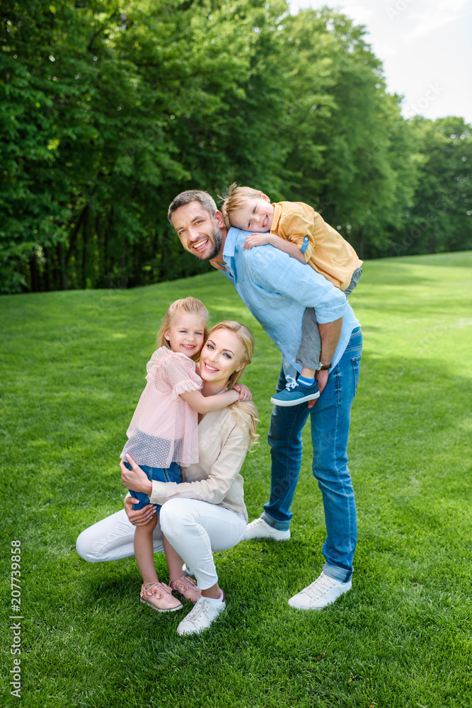happy family smiling at camera while spending time together in park happy family smiling at camera while spending time together in park