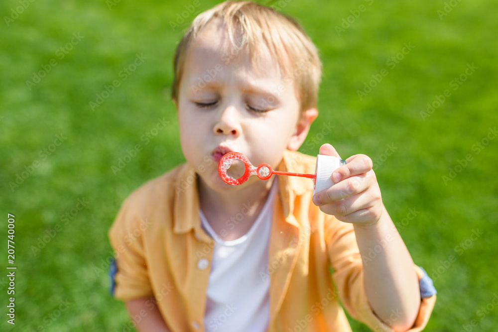 cute little boy with closed eyes blowing soap bubbles in park cute little boy with closed eyes blowing soap bubbles in park