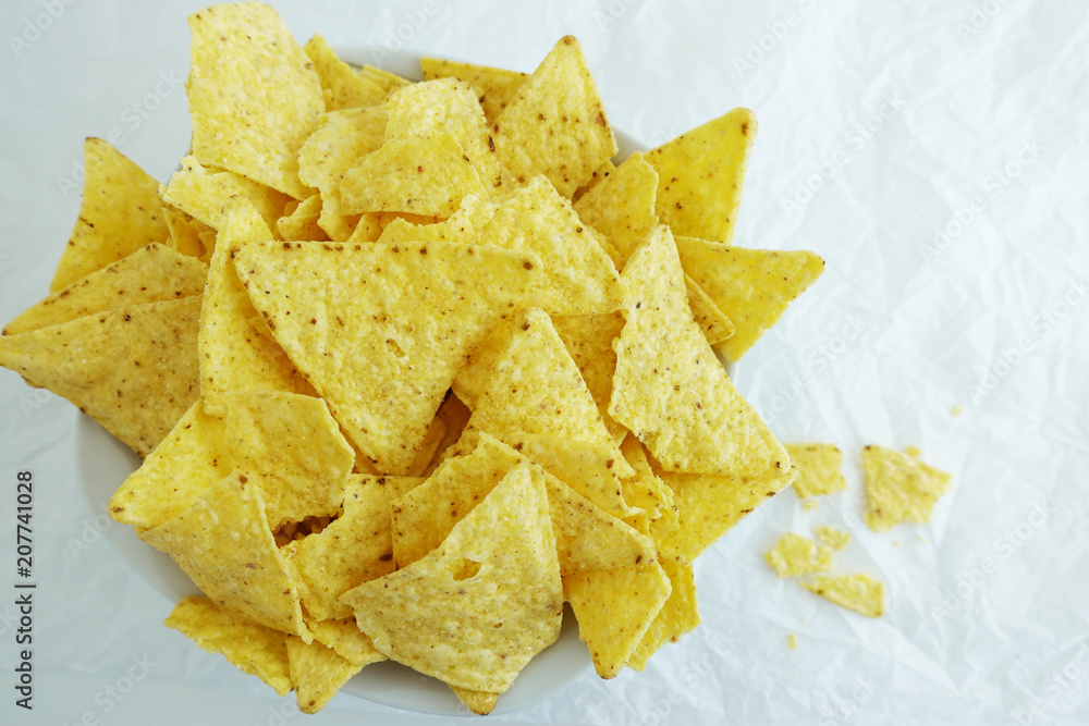 Traditional Mexican tortilla chips or nachos on white paper background

