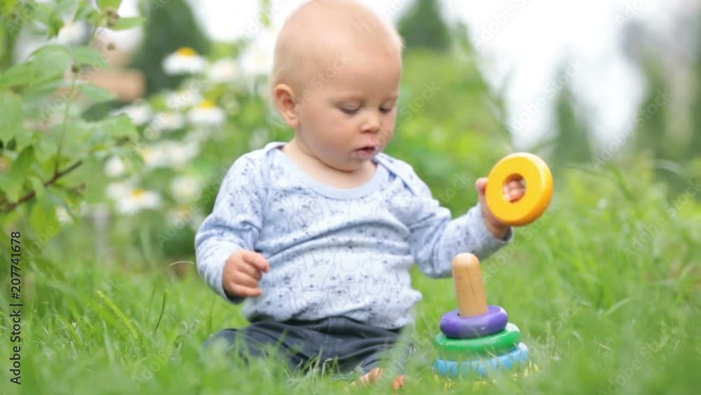 Little baby boy, playing with big construction blocks in garden, building different shapes Little baby boy, playing with big construction blocks in garden, building different shapes