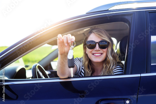 Woman sitting in the car and holding a white blank poster.