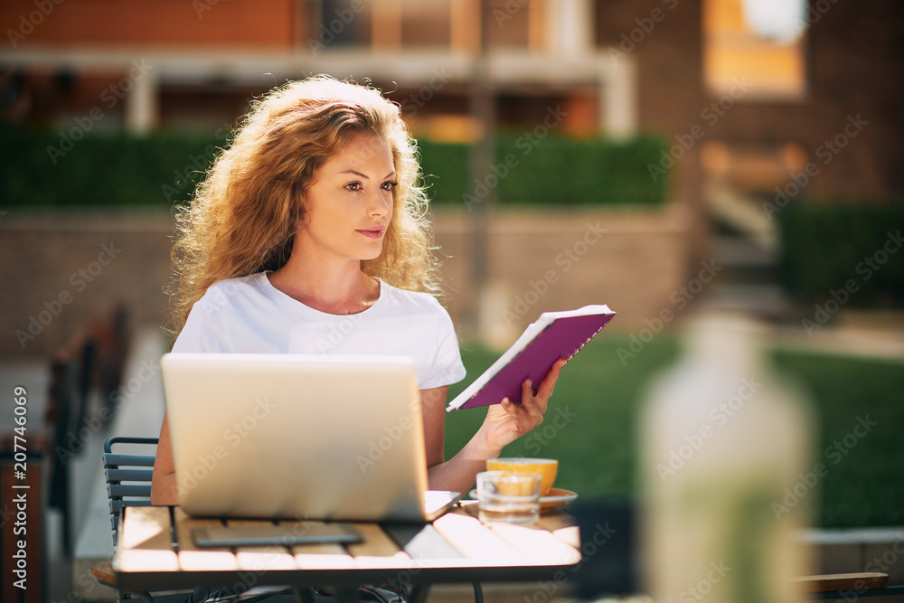 Female student using laptop for writting essay while sitting in cafe. Female student using laptop for writting essay while sitting in cafe.