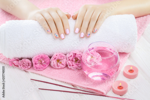 beautiful pink manicure with tea rose, candle and towel on the white wooden table.
