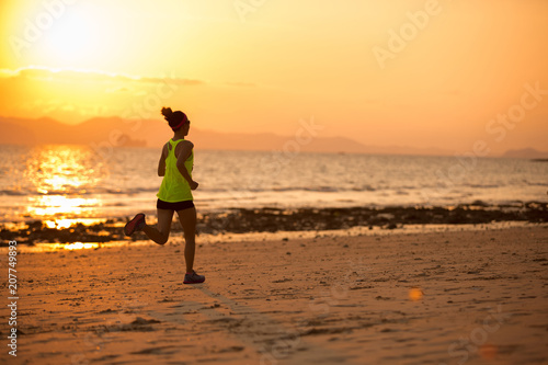 Young woman running at sunset sandy beach