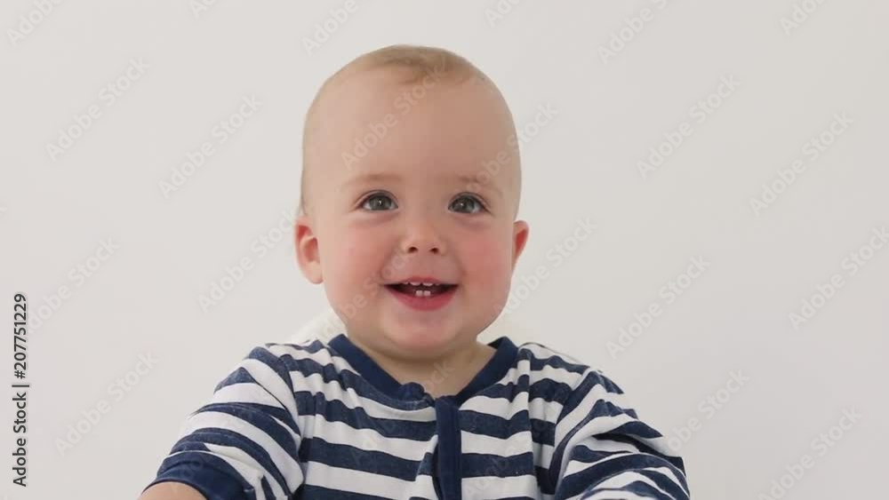 Crop cute infant pointing with finger and smiling on white background Crop cute infant pointing with finger and smiling on white background