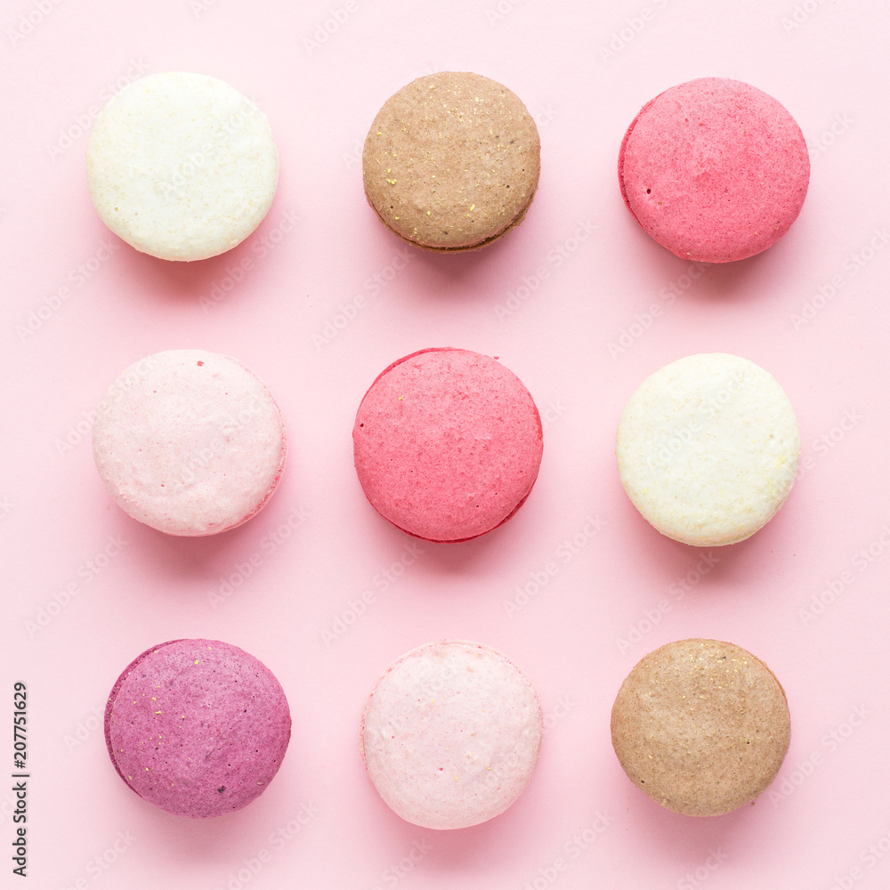 Fototapeta premium Colorful cake macaron or macaroon isolated over pastel pink background. Top view
