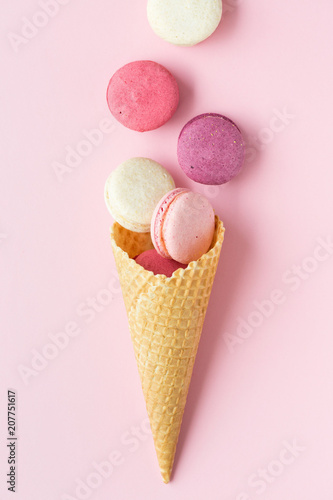 Flatlay of pastel cake macaron or macaroon and sweet cones over pastel pink background. Top view with space for your text