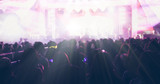 blurry of silhouettes of concert crowd at Rear view of festival crowd raising their hands on bright stage lights