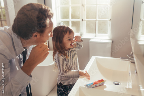 Schilderij op canvas Father teaching daughter how to brush teeth