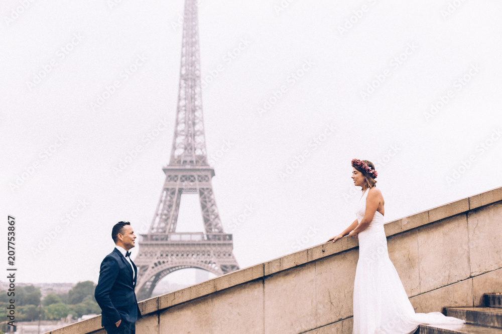 Newly-wed couple on their honeymoon in Paris, loving having a date near the Eiffel tower