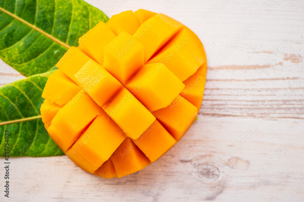 Fresh and beautiful mango fruit with sliced diced mango chunks on a light wooden background, copy space(text space), blank for text, top view. Fresh and beautiful mango fruit with sliced diced mango chunks on a light wooden background, copy space(text space), blank for text, top view.