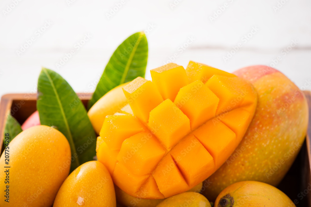 Fresh and beautiful mango fruit set in a wooden box with sliced diced mango chunks on a light wooden background, copy space(text space), blank for text Fresh and beautiful mango fruit set in a wooden box with sliced diced mango chunks on a light wooden background, copy space(text space), blank for text