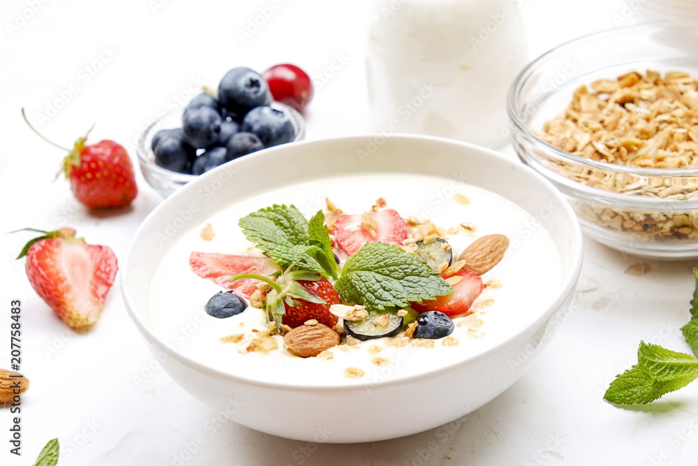 Serving option of granola bowl with mix of nuts, cereals, fruits and berries, greek yogurt. Healthy vegetarian breakfast, organic strawberry, blueberry, mint, almond. Close up, top view, background. Serving option of granola bowl with mix of nuts, cereals, fruits and berries, greek yogurt. Healthy vegetarian breakfast, organic strawberry, blueberry, mint, almond. Close up, top view, background.