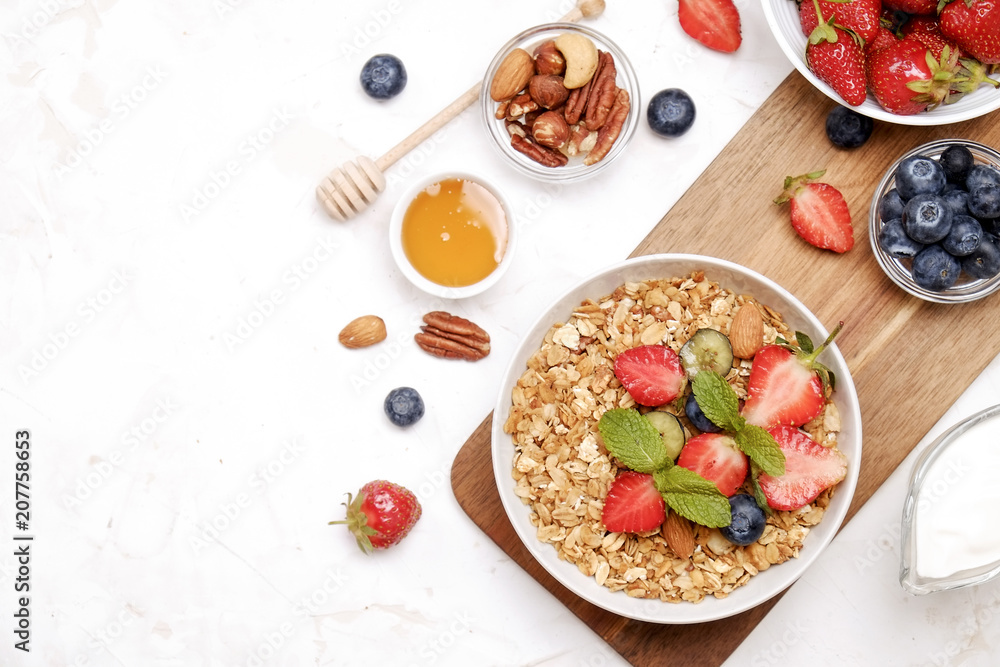 Serving option of granola bowl with mix of nuts, cereals, fruits and berries, greek yogurt. Healthy vegetarian breakfast, organic strawberry, blueberry, mint, almond. Close up, top view, background. Serving option of granola bowl with mix of nuts, cereals, fruits and berries, greek yogurt. Healthy vegetarian breakfast, organic strawberry, blueberry, mint, almond. Close up, top view, background.