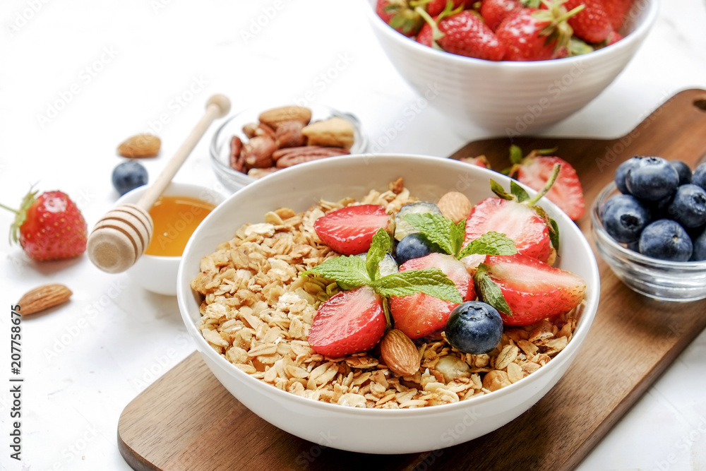 Serving option of granola bowl with mix of nuts, cereals, fruits and berries, greek yogurt. Healthy vegetarian breakfast, organic strawberry, blueberry, mint, almond. Close up, top view, background. Serving option of granola bowl with mix of nuts, cereals, fruits and berries, greek yogurt. Healthy vegetarian breakfast, organic strawberry, blueberry, mint, almond. Close up, top view, background.