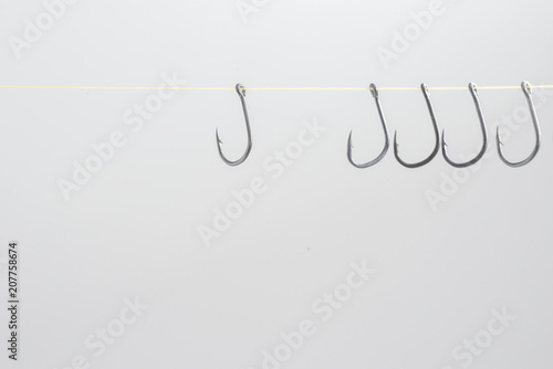 Hooked hooks with yellow ropes hang many together on a white bac
