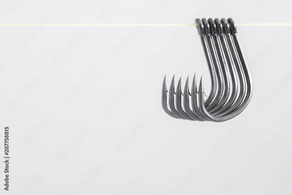 Hooked hooks with yellow ropes hang many together on a white bac