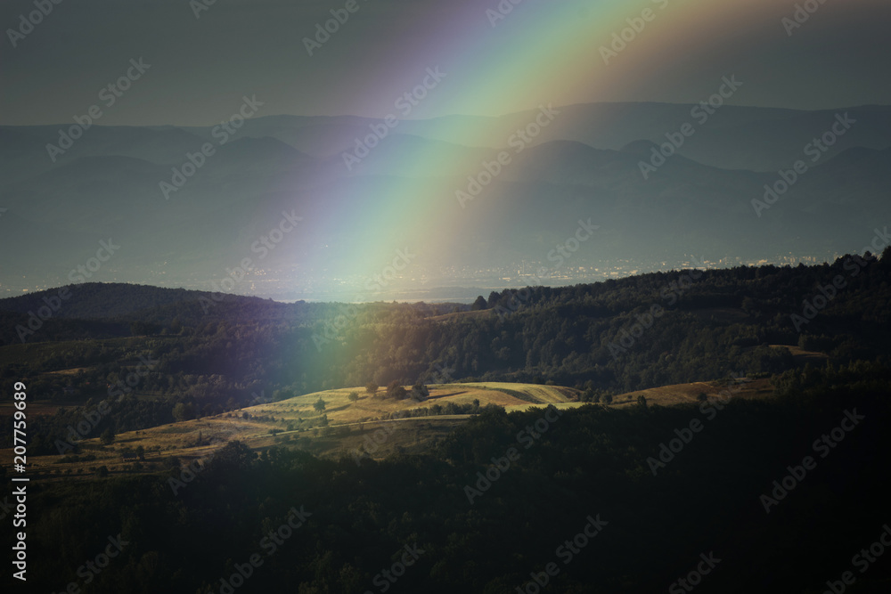 rainbow landscape, summer evening with rainbow over hills