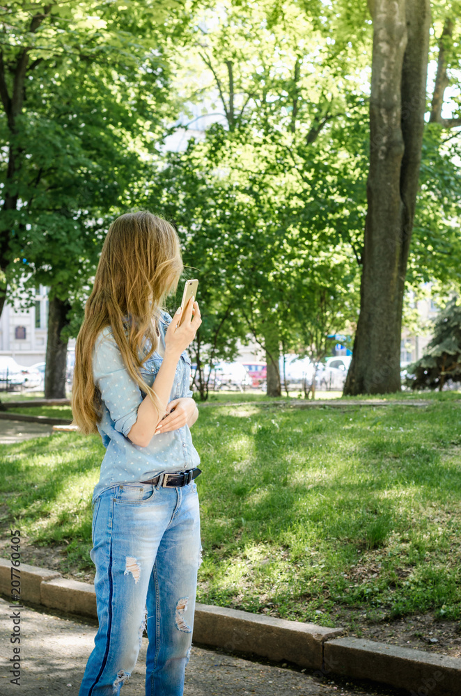 Smiling bussines casual woman holding call smartphone mobile cell with long hair in green nature park sunny day background Smiling bussines casual woman holding call smartphone mobile cell with long hair in green nature park sunny day background