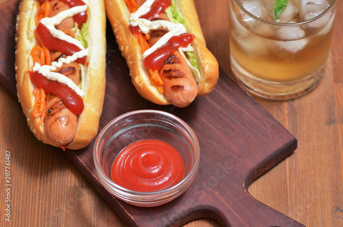 Delicious hot dogs with grilled sausage, vegetables, greens and sauces